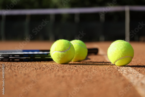 Tennis balls and racket on clay court