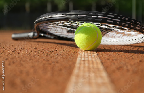 Tennis ball and racket on clay court, closeup