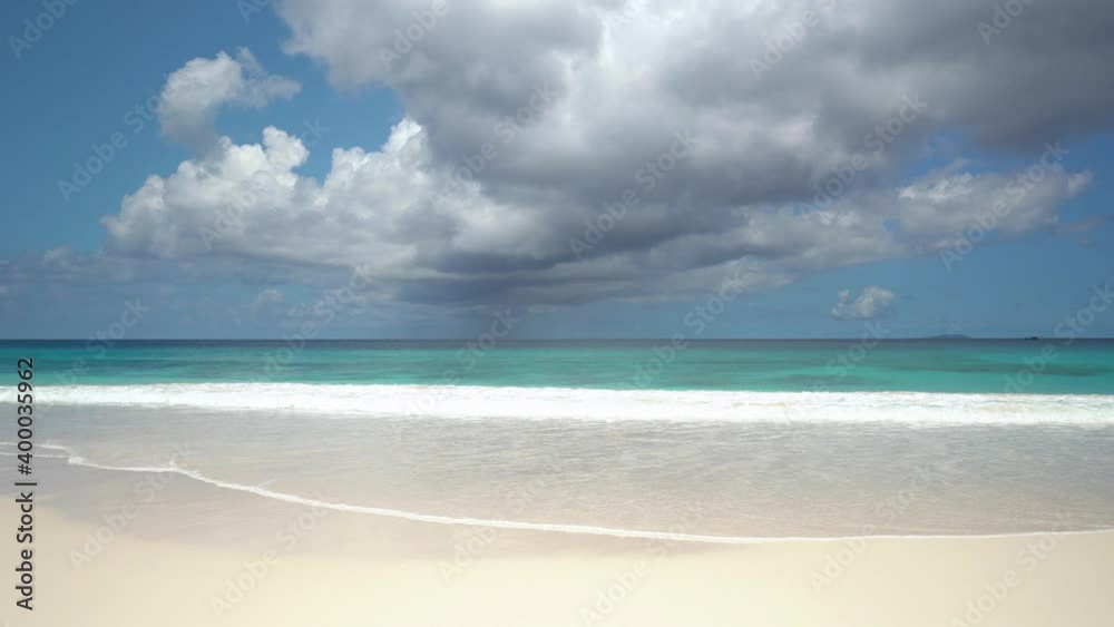 Exotic beach by the ocean with rolling waves on the sandy shore and blue sky Exotic beach by the ocean with rolling waves on the sandy shore and blue sky