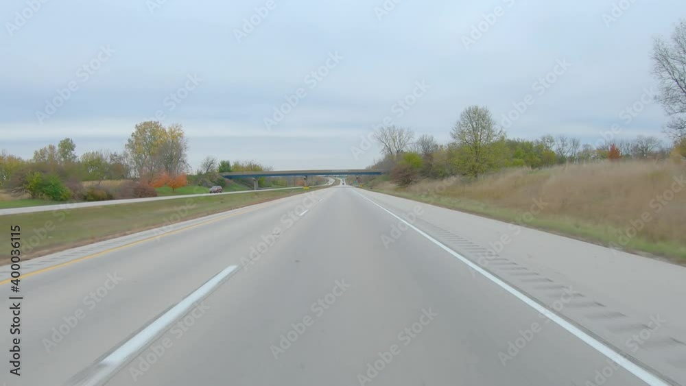 POV driving on a interstate highway past harvested fields on a cloudy winter day in rural western Illinois; rural agricultural landscape with gentle rolling hills POV driving on a interstate highway past harvested fields on a cloudy winter day in rural western Illinois; rural agricultural landscape with gentle rolling hills