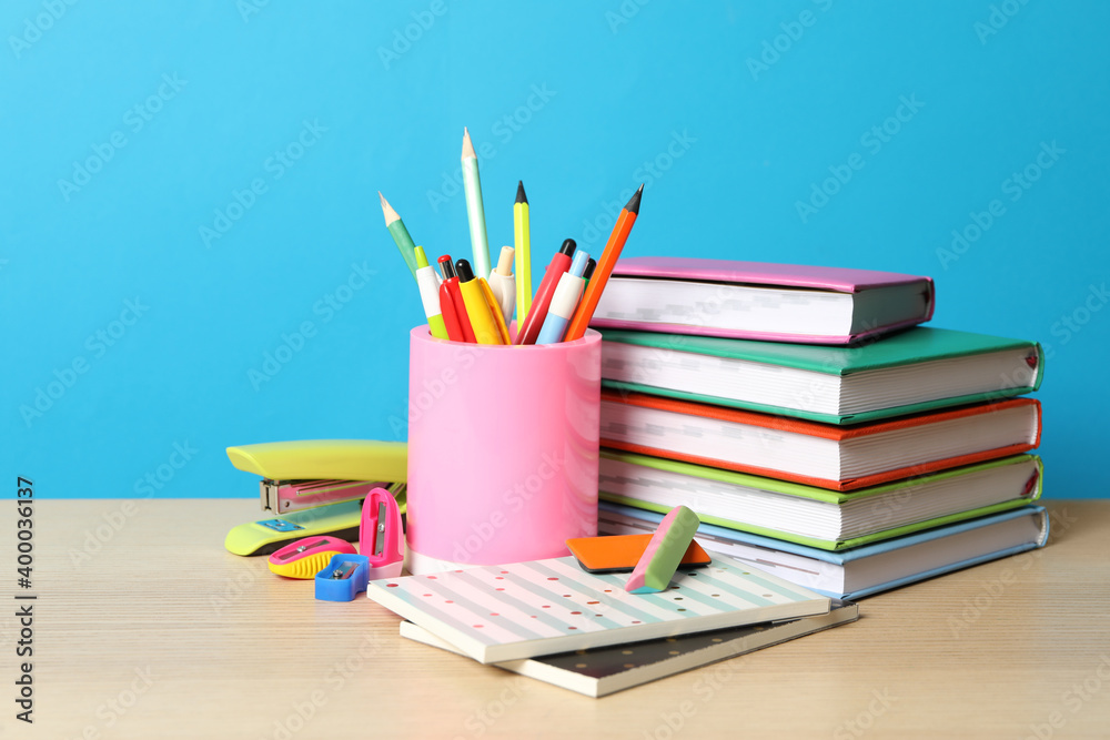 Composition with different school stationery on wooden table against light blue background. Back to school Composition with different school stationery on wooden table against light blue background. Back to school