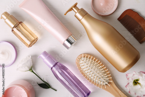Flat lay composition with different hair products and accessories on white wooden table