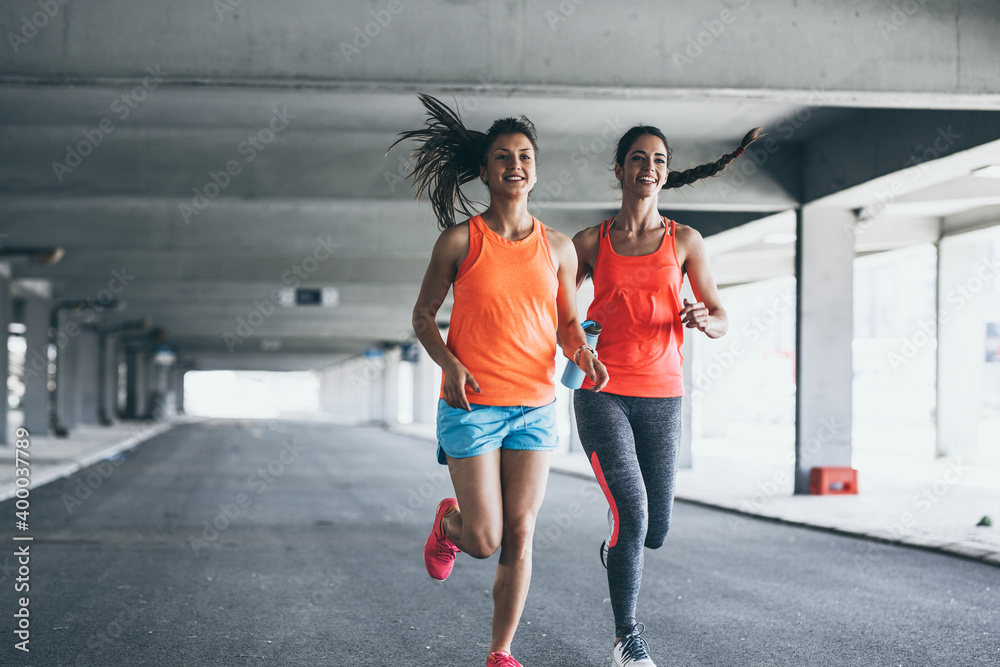 Obraz premium Two female runners jogging around the city .Urban workout concept. 