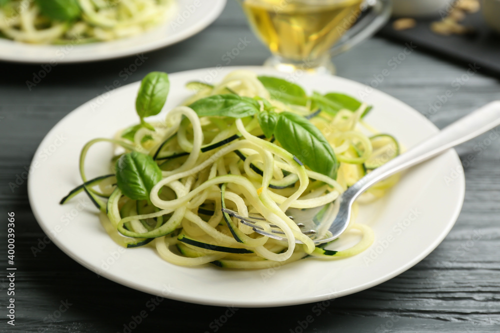 Delicious zucchini pasta with basil served on grey wooden table, closeup