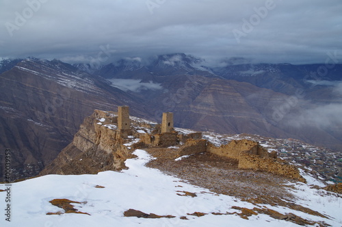 At the edge of cliff. View of canyon and river, mountain range and ancient aul Goor with defensive and military towers. Nature and travel. Russia, North Caucasus, Dagestan, Shamilsky District photo