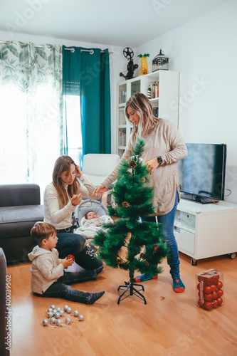 Lesbian mothers decorating the Christmas tree with their two children