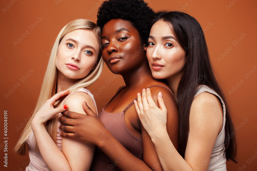 young pretty asian, caucasian, afro woman posing cheerful together on brown background, lifestyle diverse nationality people concept young pretty asian, caucasian, afro woman posing cheerful together on brown background, lifestyle diverse nationality people concept