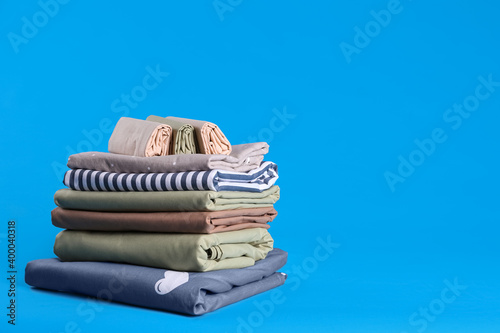 Stack of clean bed sheets on blue background. Space for text © New Africa