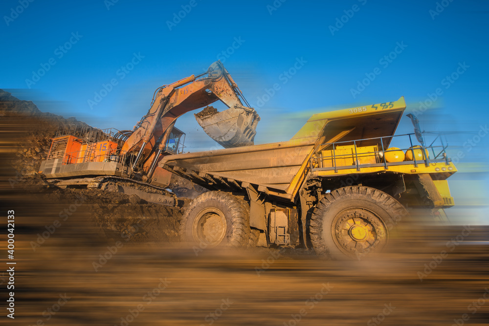 Obraz premium Big yellow dump truck and excavator in coal mine 