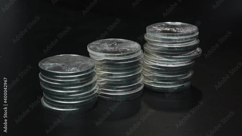 Silver coins (American Silver Eagles) being stacked by hand Silver coins (American Silver Eagles) being stacked by hand