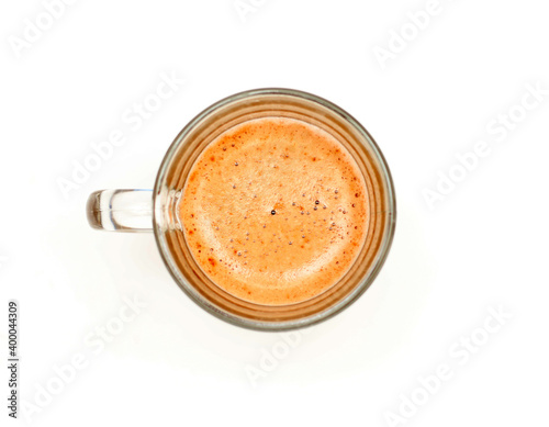 Thick foam on in a transparent glass cup with coffee on a white background, studio photo