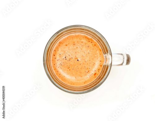 Thick foam on in a transparent glass cup with coffee on a white background, top view studio photo