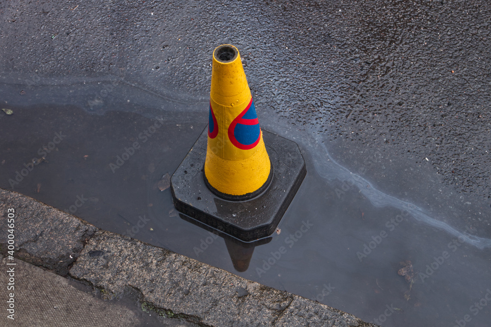 Traffic cone on the street in a puddle
