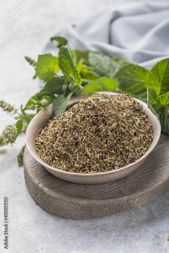 Fresh green peppermint leaves and dried mint leaves in bowl on rustic table. Dry spice concept