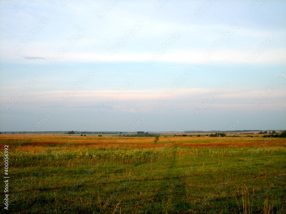 A flat horizon line between the sky and the earth. The sky and clear field in the countryside are illuminated by the rays of the setting sun. A flat horizon line between the sky and the earth. The sky and clear field in the countryside are illuminated by the rays of the setting sun.