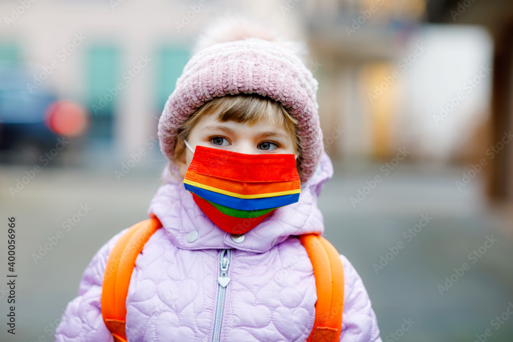 Little kid girl wearing medical mask on the way to kindergarten, playschool or nursery. Child with backpack satchel on cold day with warm clothes. Lockdown and quarantine time during corona pandemic Little kid girl wearing medical mask on the way to kindergarten, playschool or nursery. Child with backpack satchel on cold day with warm clothes. Lockdown and quarantine time during corona pandemic