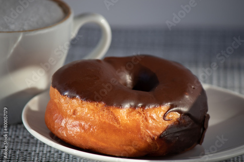 Donut with chocolate on a platter with a cup of coffee