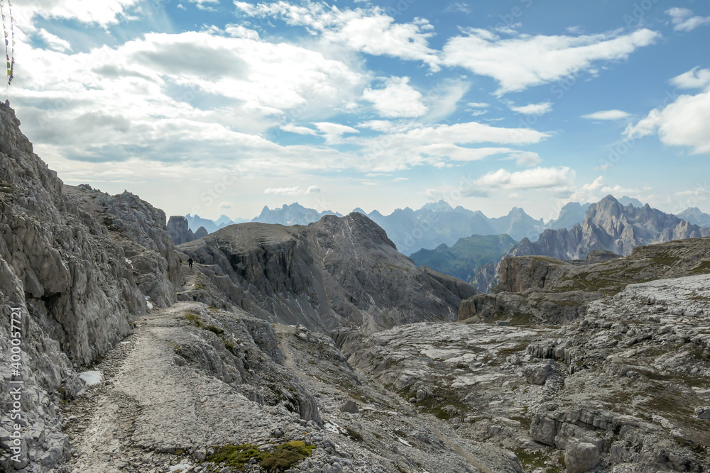 An endless view on a high and desolated mountain peaks in Italian Dolomites. The lower parts of the mountains are overgrown with moss and grass. Raw and unspoiled landscape. Few clouds above the peaks