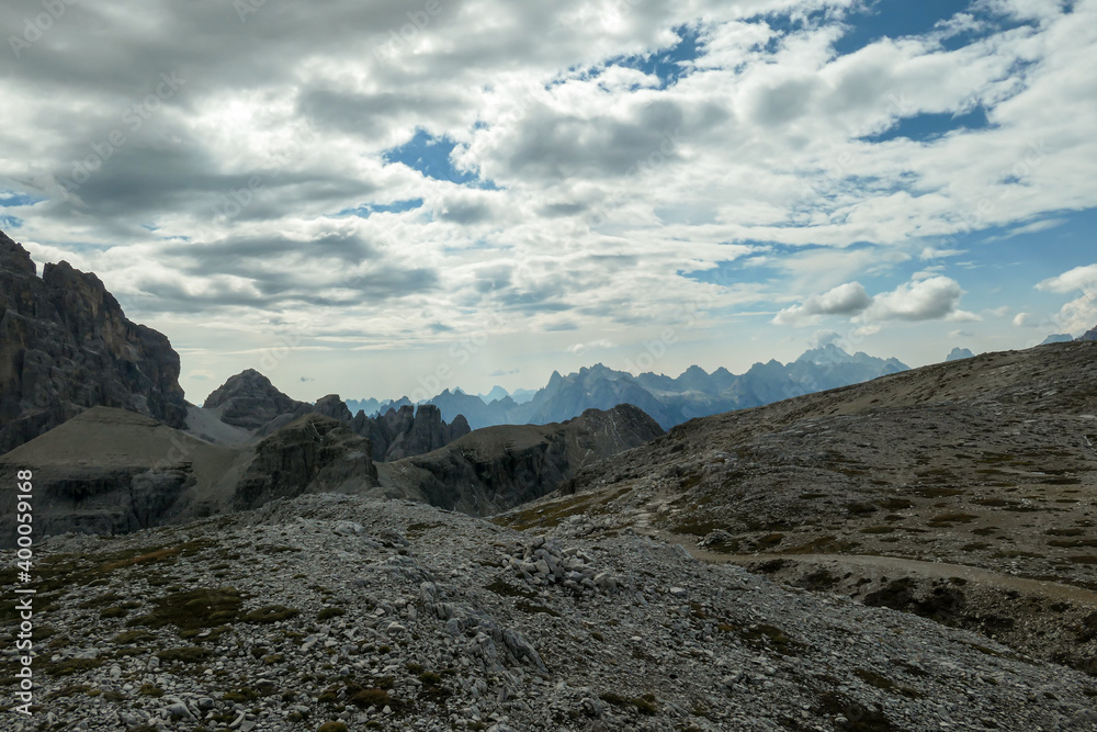 An endless view on a high and desolated mountain peaks in Italian Dolomites. The lower parts of the mountains are overgrown with moss and grass. Raw and unspoiled landscape. Few clouds above the peaks