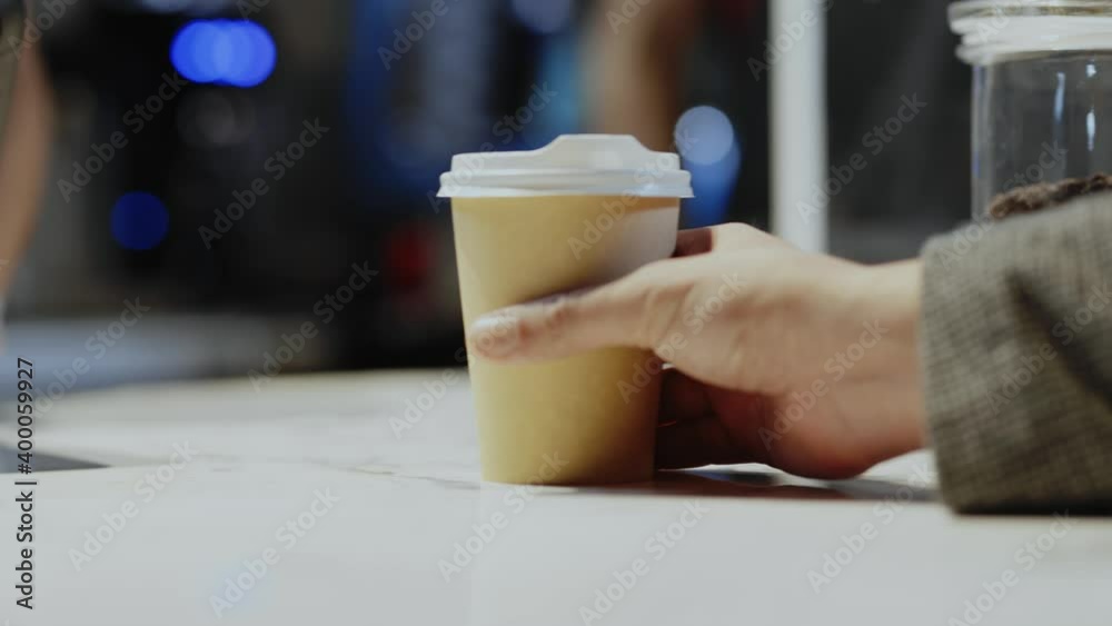 In the coffeeshop young woman waitress giving ready prepared hot takeaway coffee beverage for male client. Food and drink services. Coffee to go. Cafeteria.