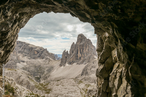 A view from a cave on distant and high mountain chain in Italian Dolomites. The mountains are steep and dangerous, with a lot of lose stones. Discovering and experiencing. Overcast