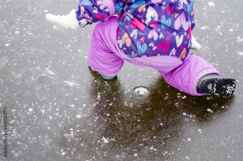 Child toddler falling on icy slippery pavement or sidewalk in winter. Slipped on the icy path. Concept of injury risk in winter. Dangerously slippery for pedestrian