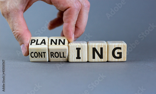 Planning or controlling symbol. Male hand flips wooden cubes and changes words 'planning' to 'controlling'. Beautiful grey background, copy space. Business and planning or controlling concept.