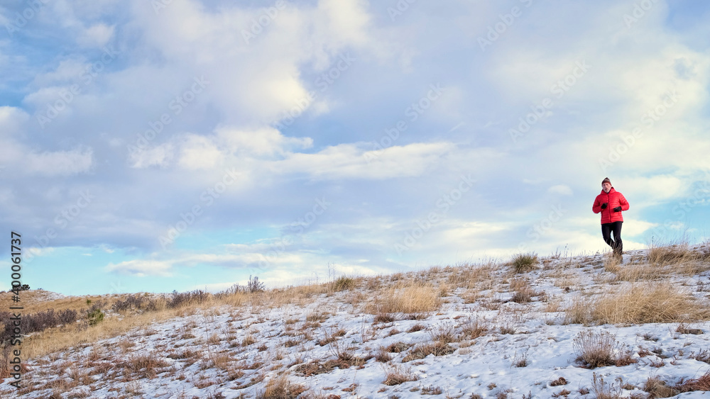 senior man is jogging at foothills of Rocky Mountains - Horsetooth Reservoir area in northern Colorado in winter scenery
