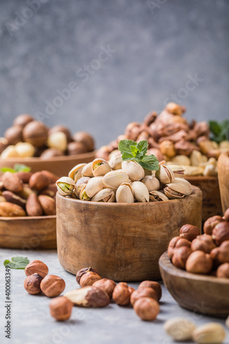 Assortment of nuts in a wooden bowls, on a gray background. Hazelnuts, pistachios, almonds, brazil nut, cashews