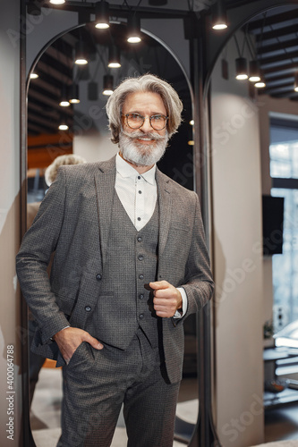 Portrait of a rich mature man. Senior visiting a fashion boutique. Male buy a new exclusive costume. photo