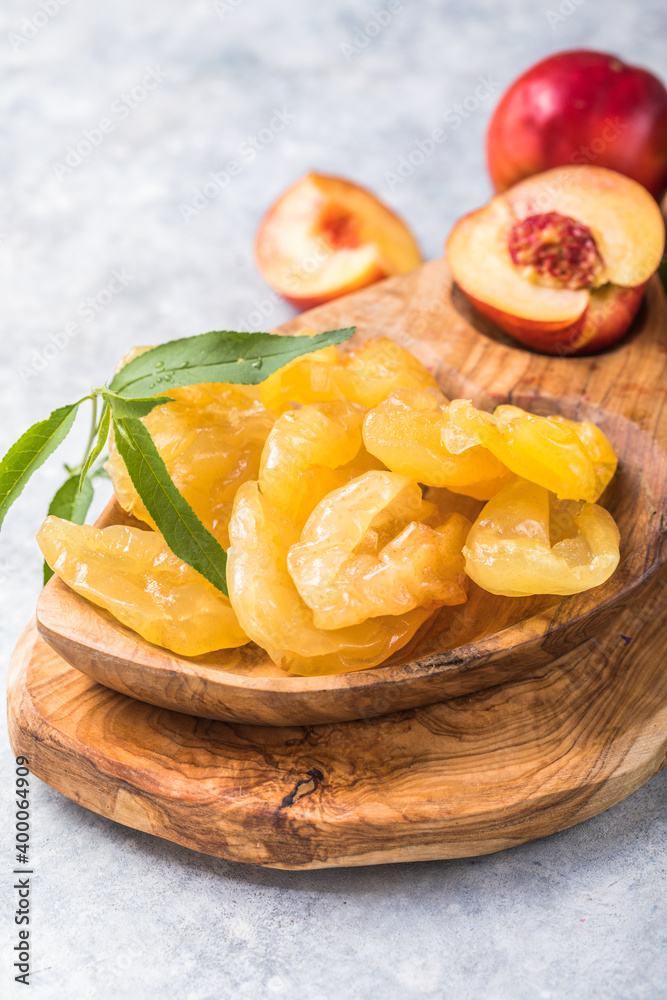 Dried fruits or candied and Fresh peaches with leaves on stone background