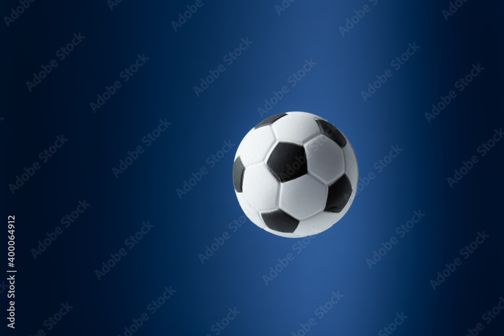 Naklejka premium Traditional soccer ball flying over blue background.