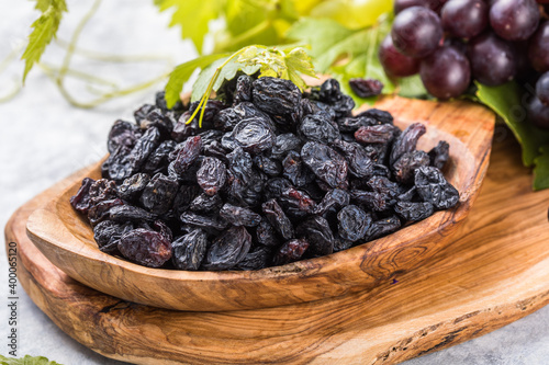 Black raisins  in bowl on stone  background, table top view. Dried fruit, healthy snack food