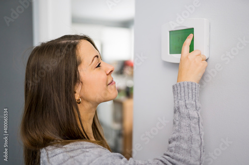 Woman set the thermostat at house. photo