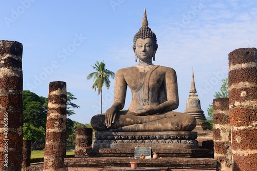 Ancient ruins and Buddha statue in the famous Sukhothai Historical Park. One of Thailand's most impressive World Heritage sites.