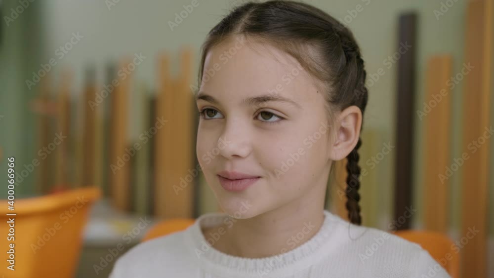 Close-up portrait of beautiful Caucasian girl sitting in classroom and talking. Charming confident intelligent schoolgirl in public school. Studying and education concept. Close-up portrait of beautiful Caucasian girl sitting in classroom and talking. Charming confident intelligent schoolgirl in public school. Studying and education concept.