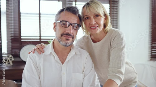 Medium close up interview shot of Caucasian man and woman talking with camera. Online meeting family for social distancing while coronavirus pandemic. Elderly couple greeting to webcam during covid-19