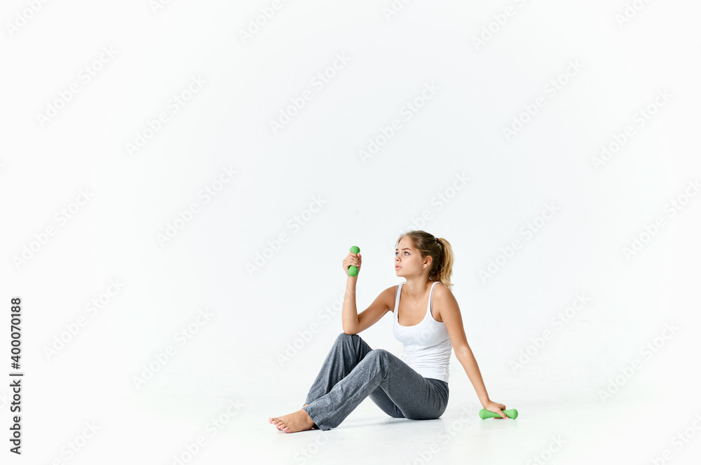 woman seroshtanov sits on the floor and a dumbbell in the background woman seroshtanov sits on the floor and a dumbbell in the background