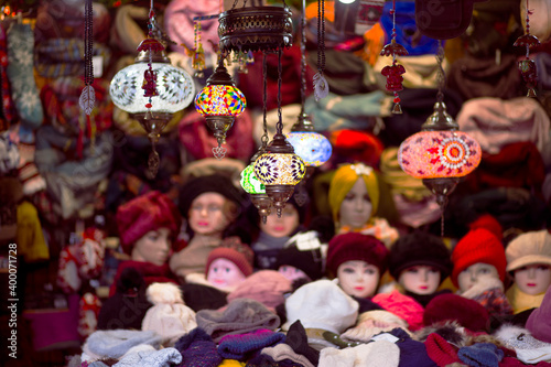 woolen hats on mannequins illuminated by decorative lamps in a Christmas street market . winter time