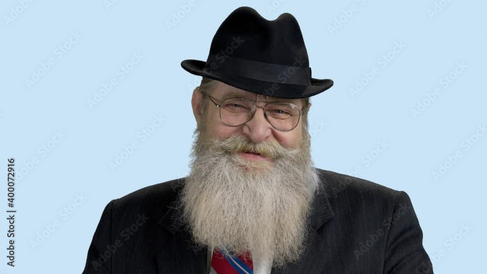 Old bearded man in hat looking at camera. Close up senior bearded man wearing suit and hat. Old bearded man in hat looking at camera. Close up senior bearded man wearing suit and hat.