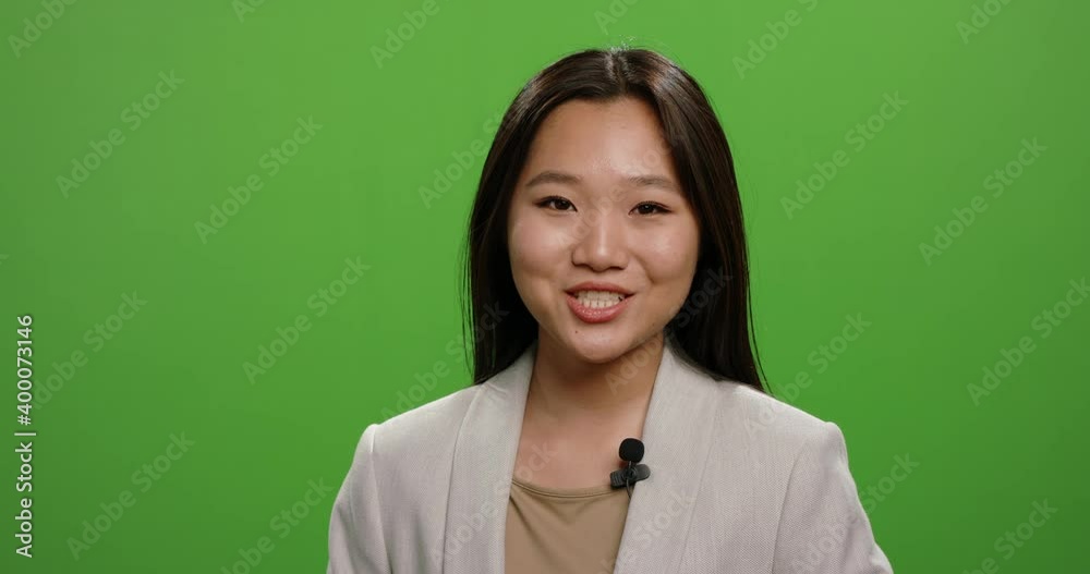Positive asian woman looking at camera and talking during an advertisement. Female anchor during morning news report, shot on green background 4k footage Positive asian woman looking at camera and talking during an advertisement. Female anchor during morning news report, shot on green background 4k footage