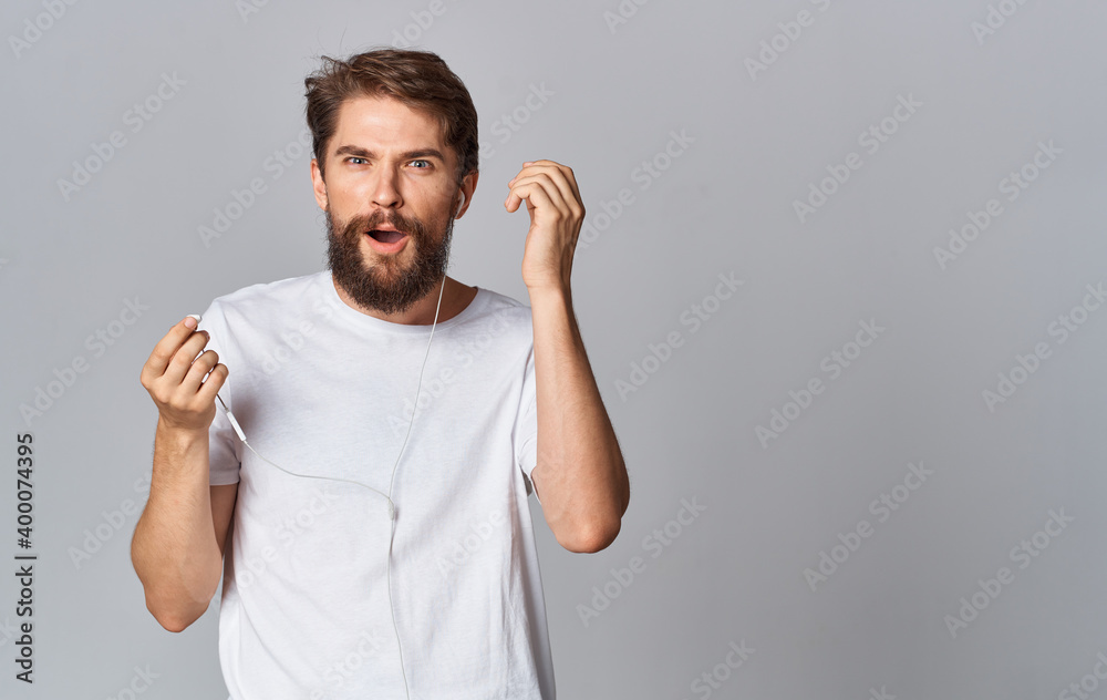 handsome man in headphones and in a white t-shirt on a gray background
