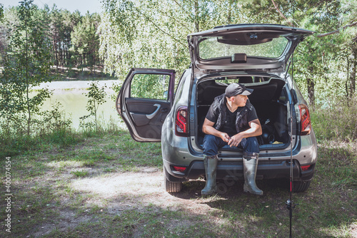 Fishing near the car in nature. Rest at nature. Man prepares fishing tackle near the car in nature. © alexey351