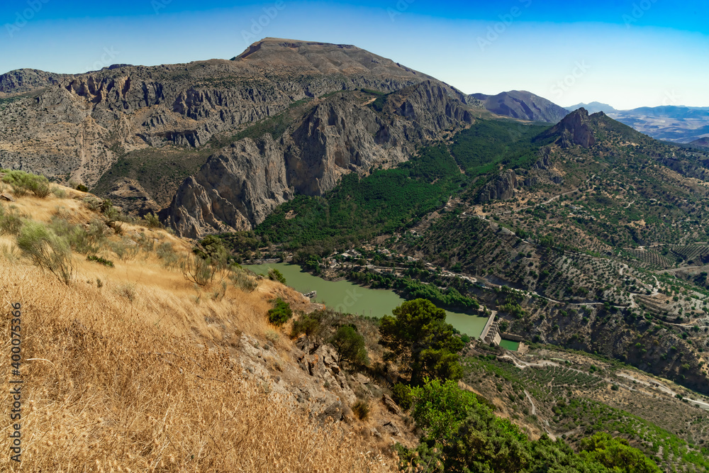 Obraz premium Paisaje de montaña con un valle, un embalse, un rio y vegetación típica mediterránea. Desde El Chorro, Álora, Málaga, Andalucía, España.