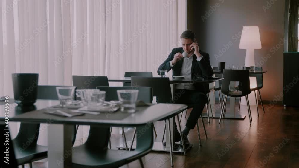 Businessman drinking out of a cup while talking on the phone Businessman drinking out of a cup while talking on the phone