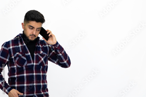 Young man wearing a dark striped shirt. He has a phone.He has a dirty beard White background. Isolated image. 