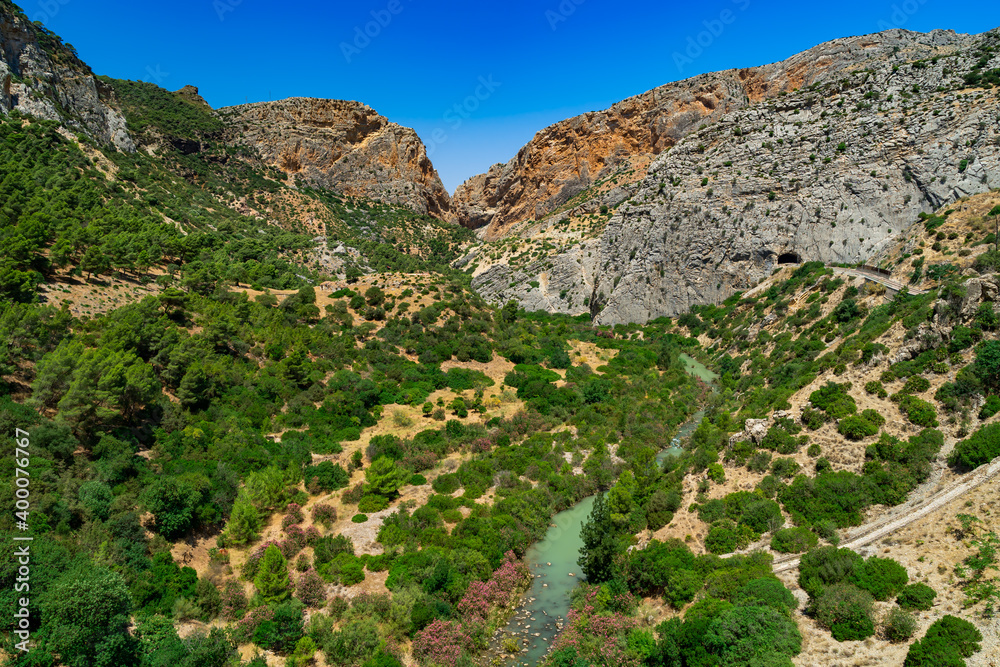 Paisaje de la naturaleza de un valle entre montañas con un rio, vegetación y cielo azul. Desde El Caminito del Rey, Málaga, Andalucía, España.