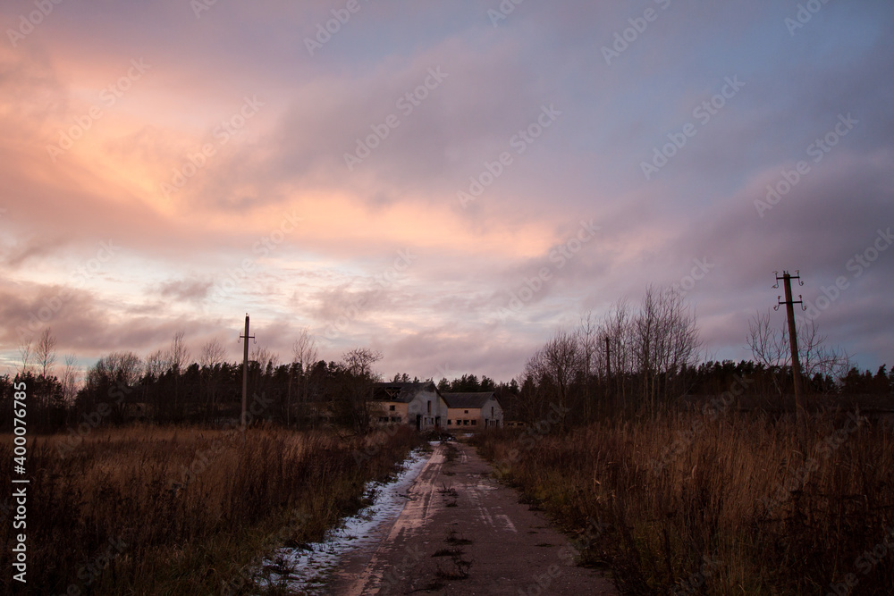 Countryside winter road in sunset light with reed, forest and cloudy sky background. Countryside winter road in sunset light with reed, forest and cloudy sky background.