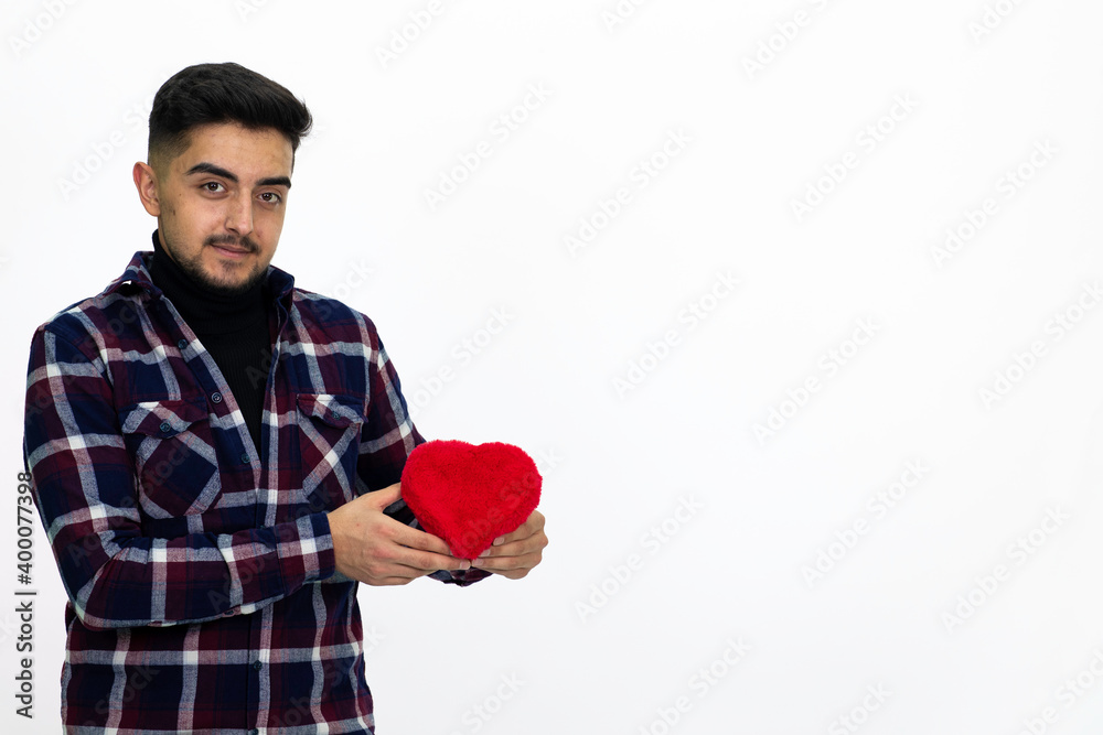 Young male holding a heart-shaped gift box in his hand. Wearing a striped shirt. Isolated image and white background. Young male holding a heart-shaped gift box in his hand. Wearing a striped shirt. Isolated image and white background.