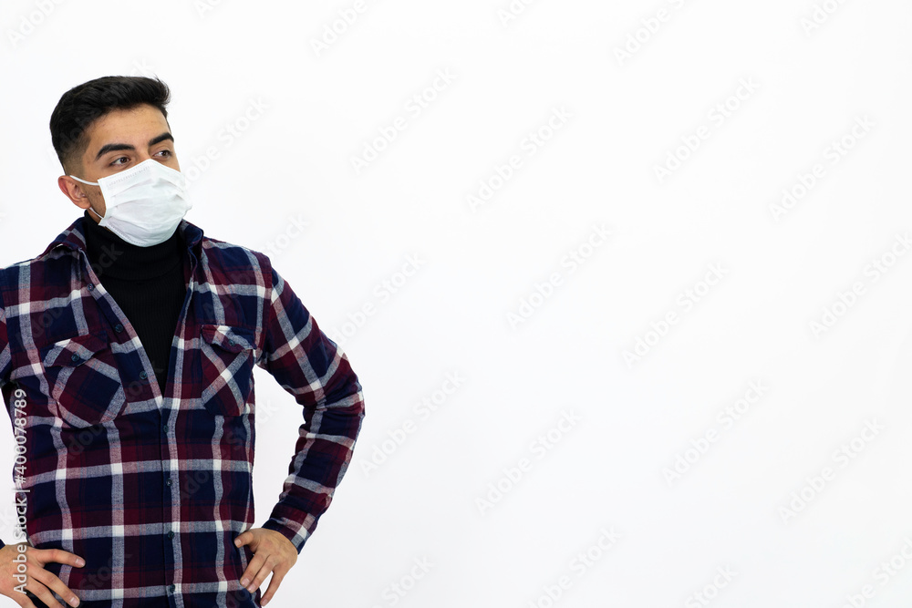 Handsome young man male model. He is wearing a medical mask and a dark checkered shirt. Handsome young man male model. He is wearing a medical mask and a dark checkered shirt.